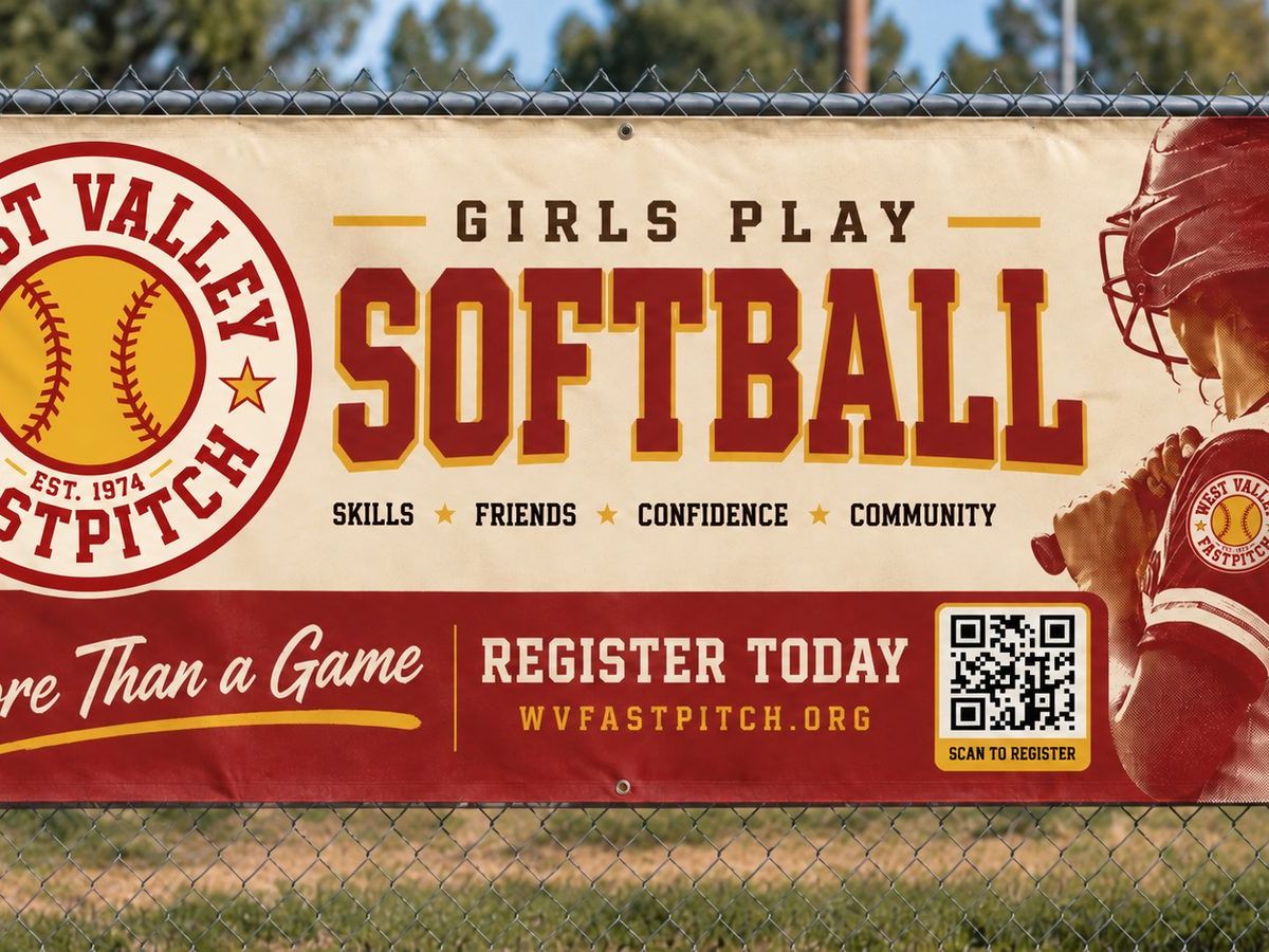 A West Valley Fast Pitch banner hanging on the outfield fence.